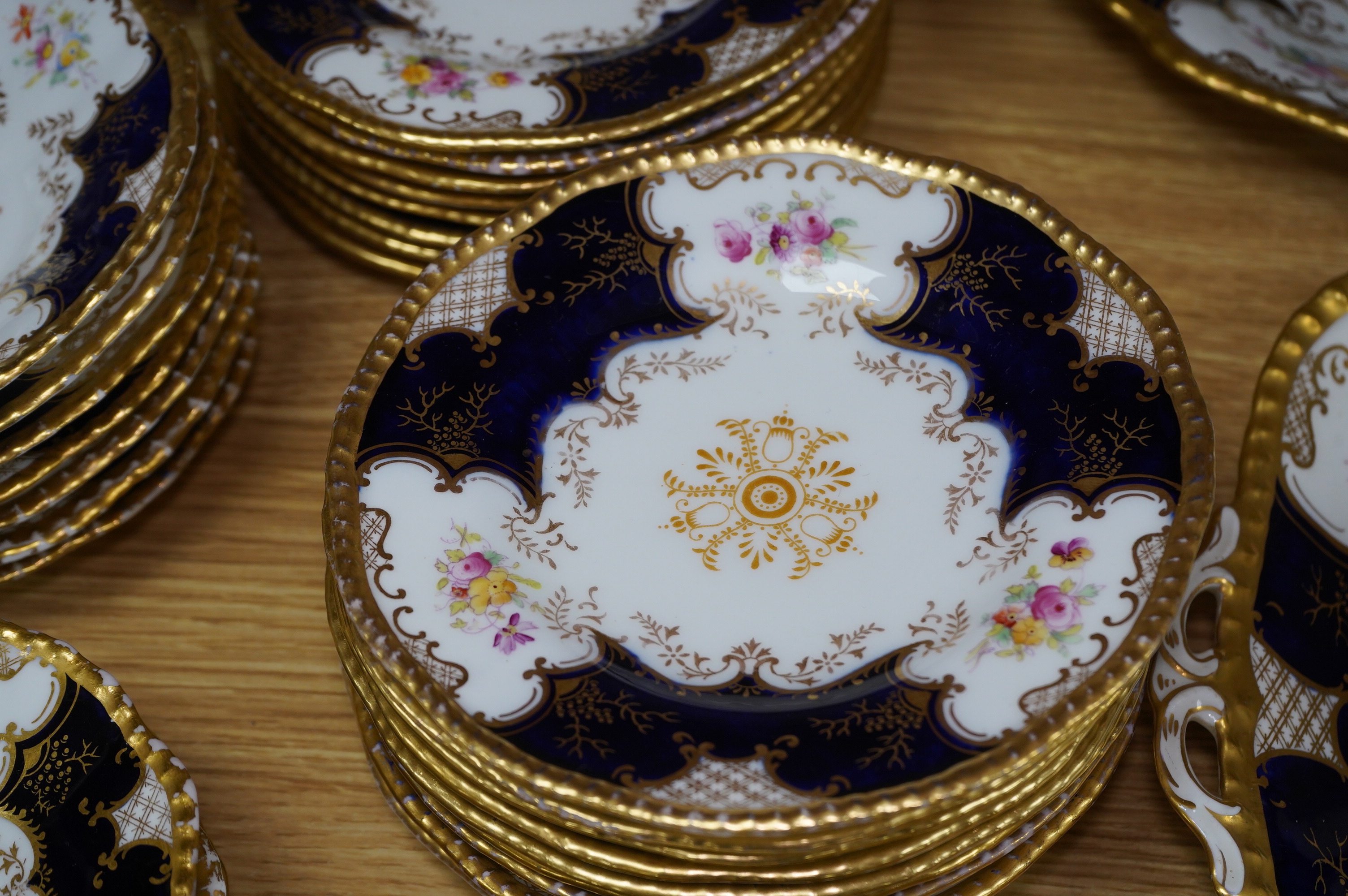 A late 19th/early 20th century Coalport blue and gilt bordered floral painted part tea and dessert service, largest 32cm wide. Condition - varies